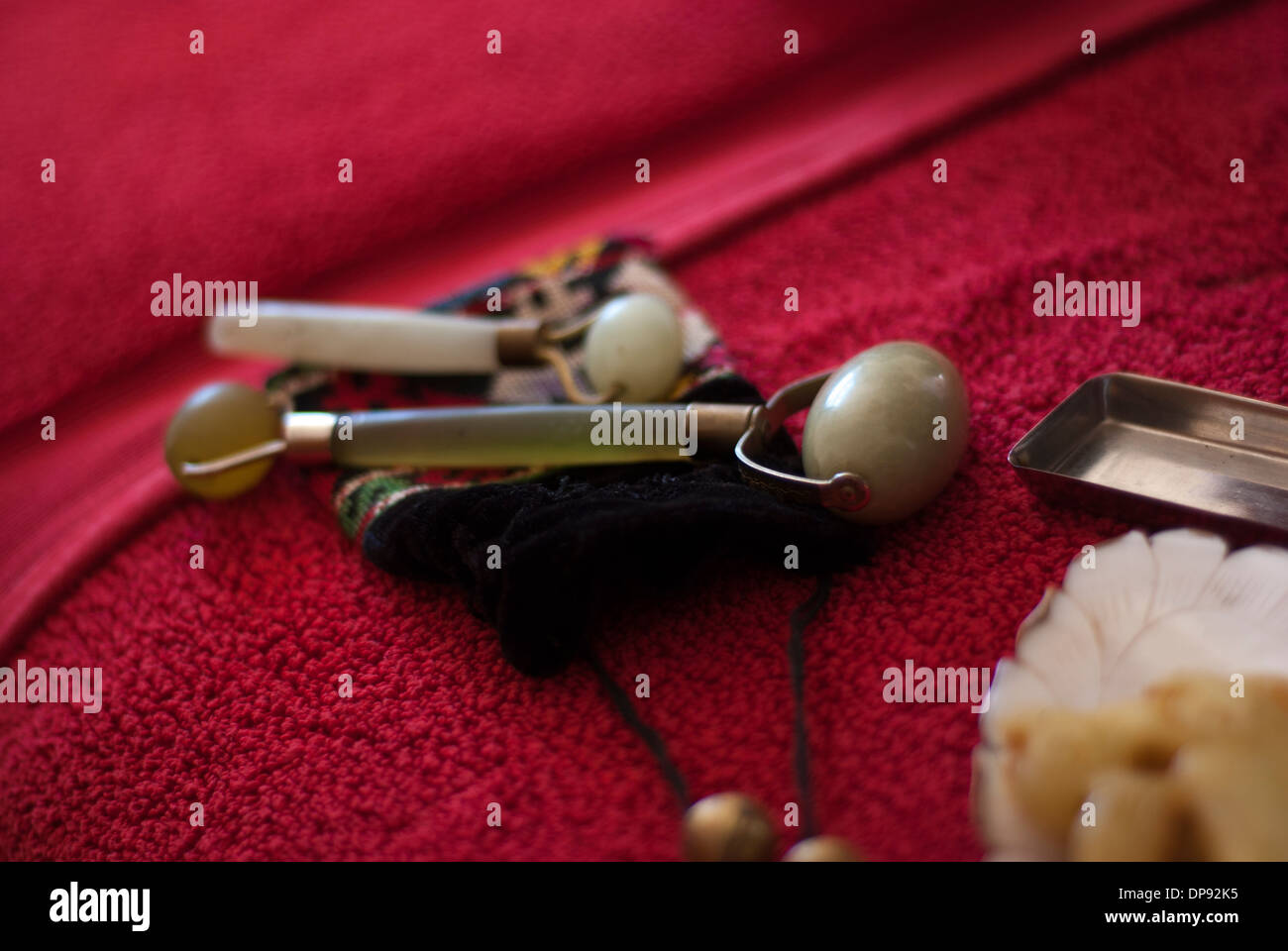Two Jade rollers on an embroidered pouch on a luxurious red spa towel. Stock Photo