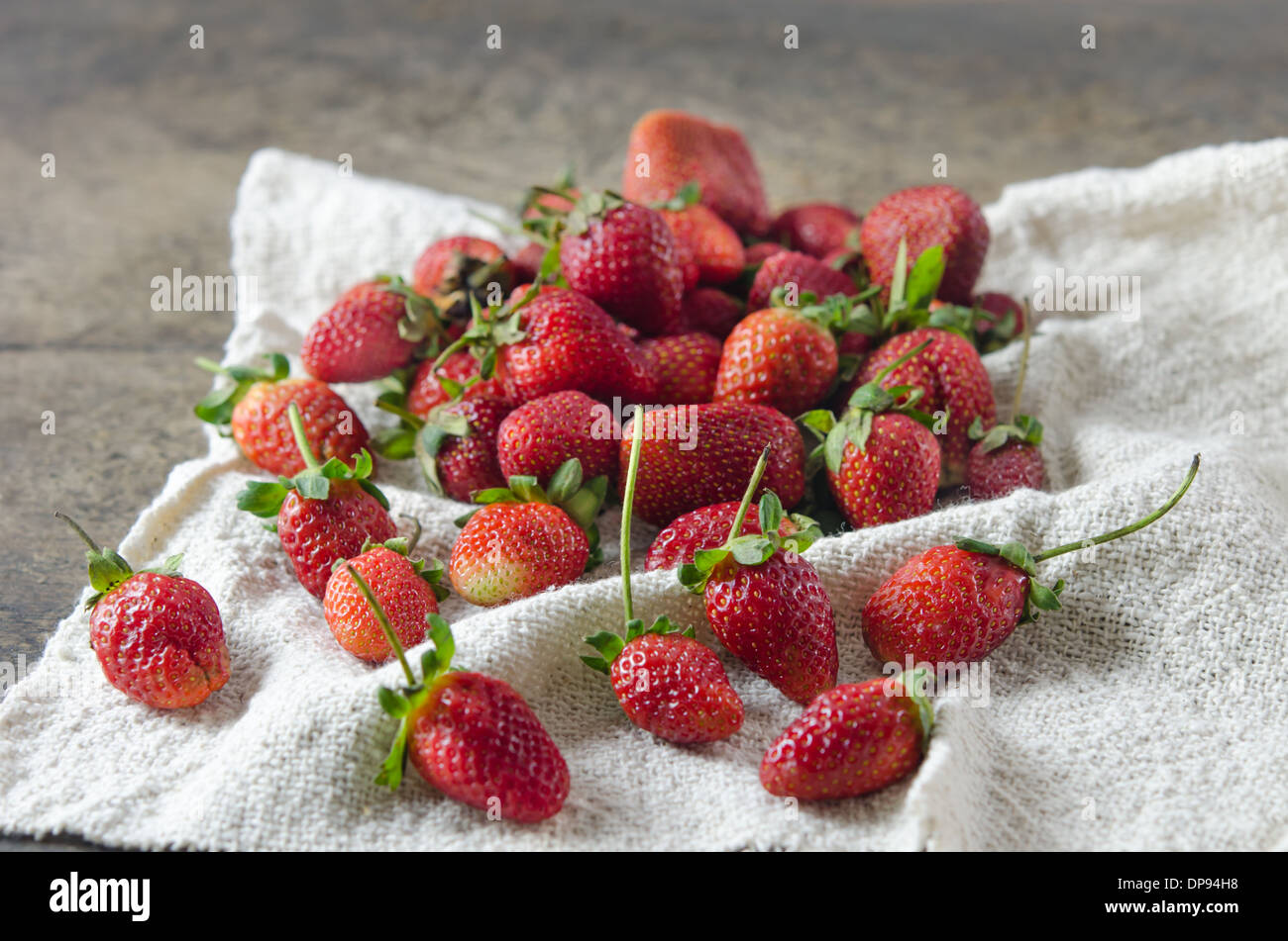 fresh ripe red strawberries on sackcloth over wooden background Stock Photo