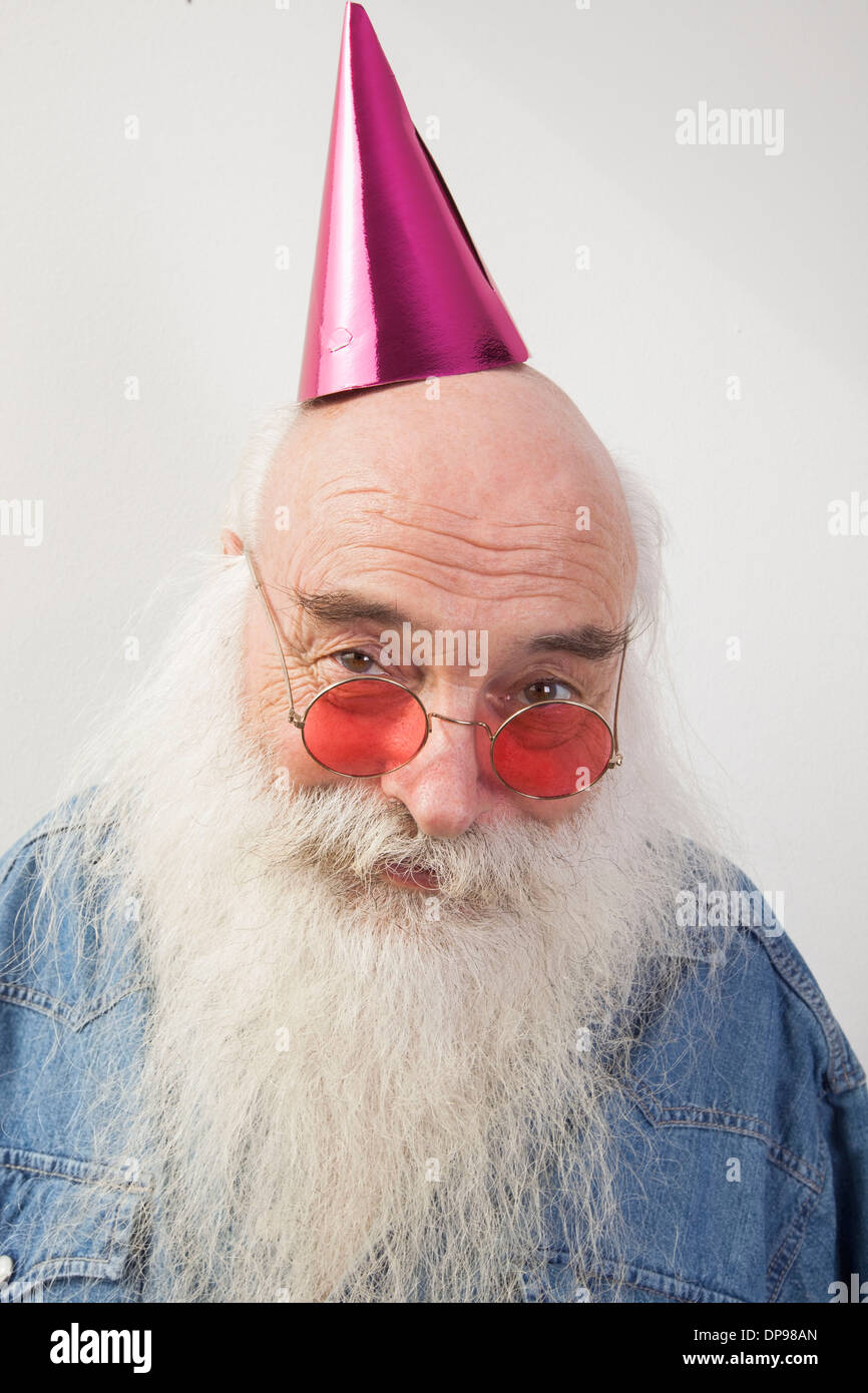 Portrait of senior man wearing red glasses and party hat over gray background Stock Photo