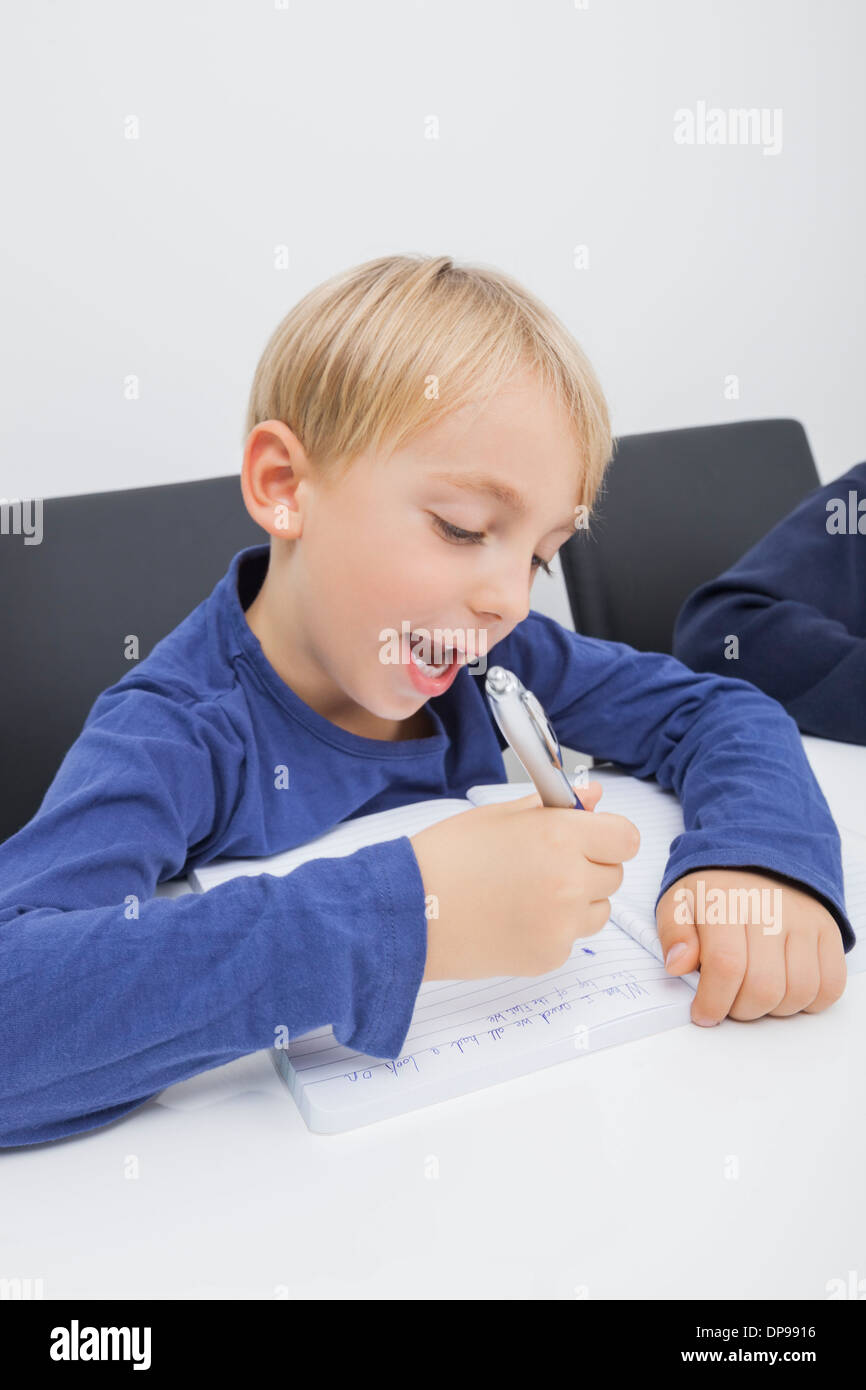 Little boy writing in book at table Stock Photo