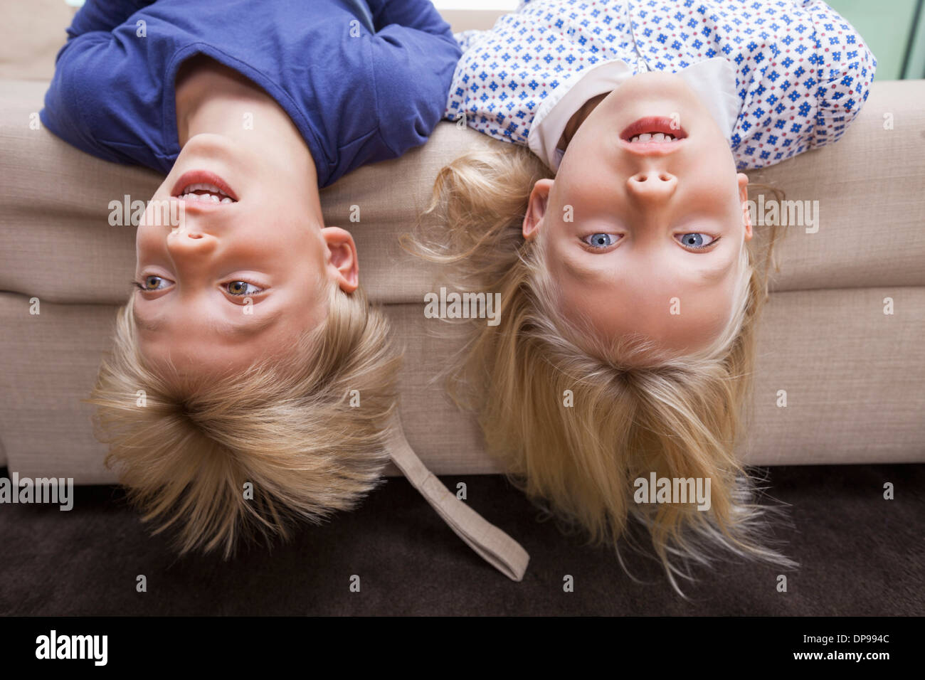 Portrait of girl with brother lying on sofa bed Stock Photo