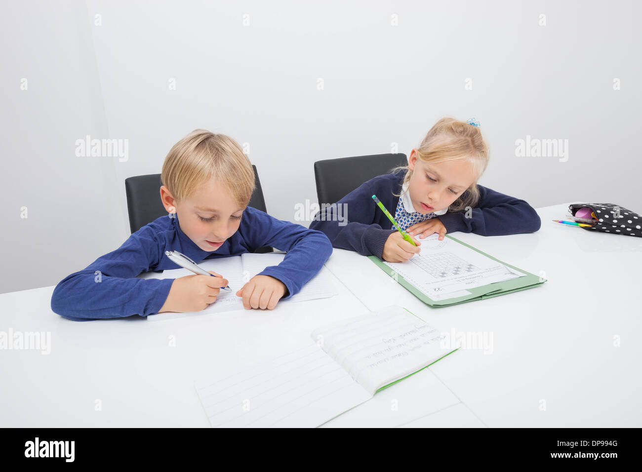 Little boy and daughter writing on documents at table Stock Photo