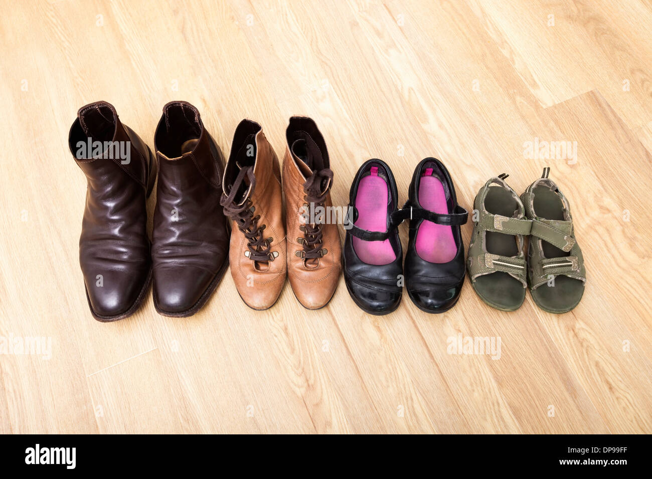 Family shoes placed in a row on hardwood floor Stock Photo