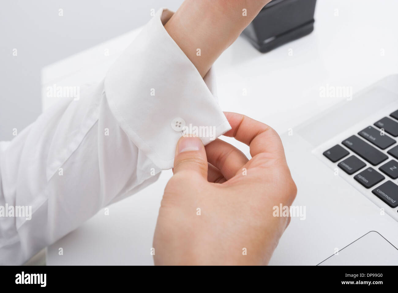 Cropped image of businessman buttoning his cuff in office Stock Photo