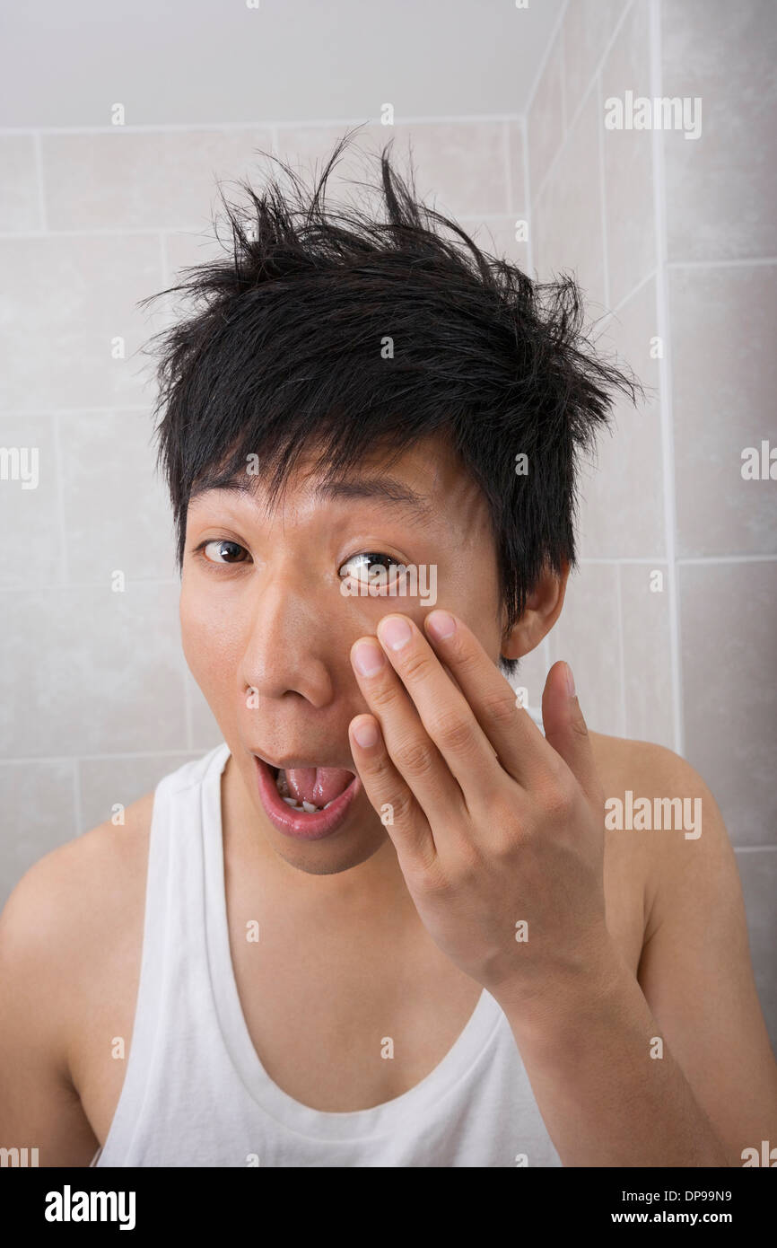 Asian mid adult man inspecting his face in bathroom Stock Photo