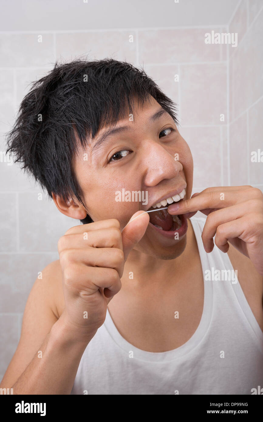 Portrait of mid adult man flossing his teeth in bathroom Stock Photo
