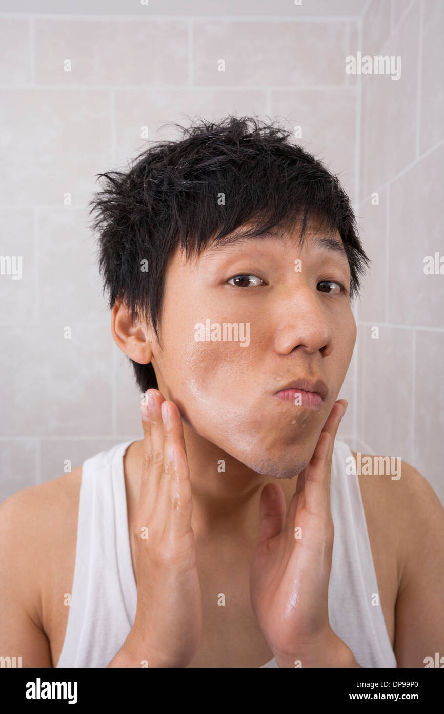 Portrait of mid adult man applying aftershave lotion in bathroom Stock Photo