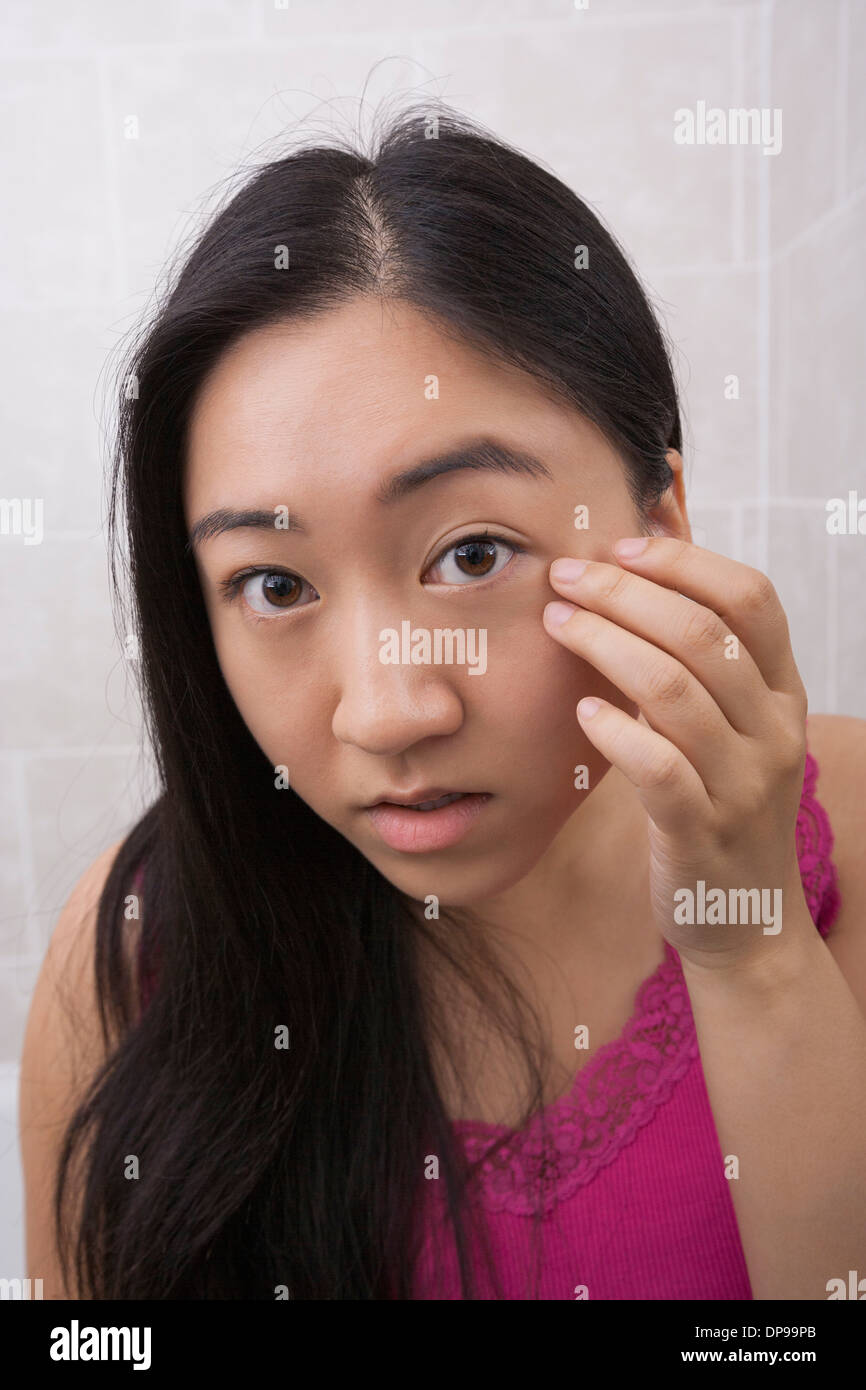 Portrait of beautiful young woman inspecting her face in bathroom Stock Photo