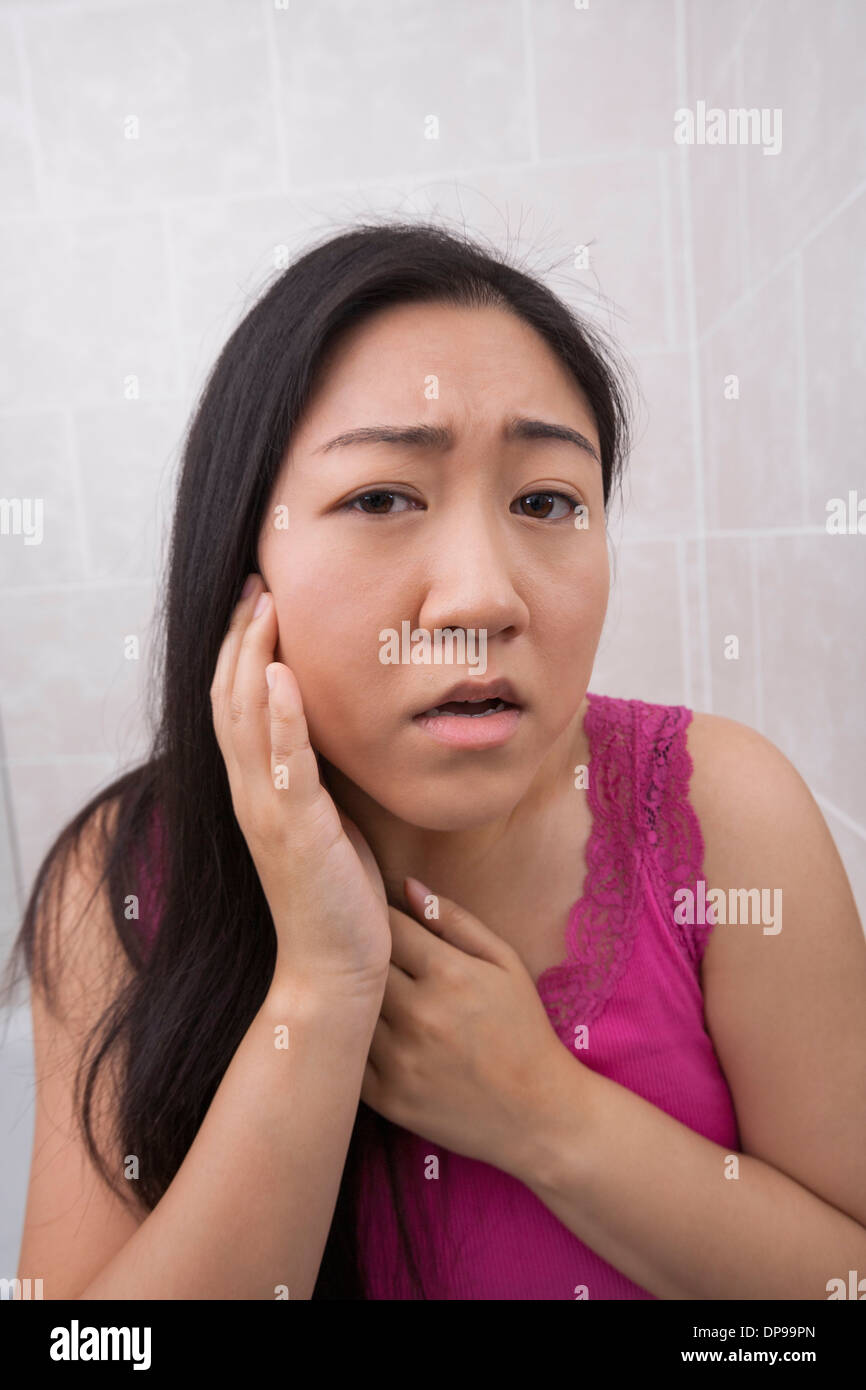 Portrait of beautiful young woman examining her face in bathroom Stock Photo