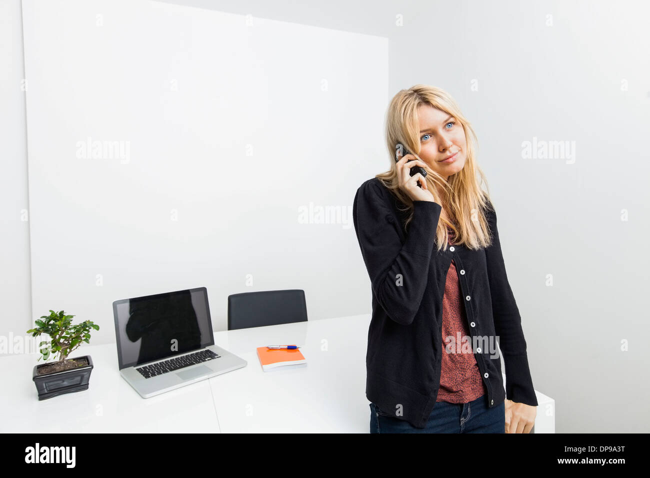 Businesswoman answering cell phone in office Stock Photo