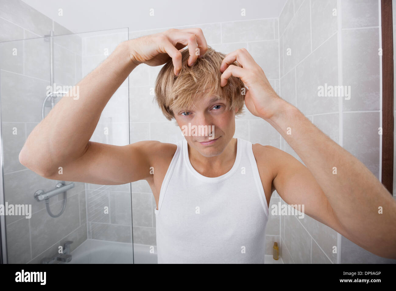 Portrait of man checking for white hair in bathroom Stock Photo