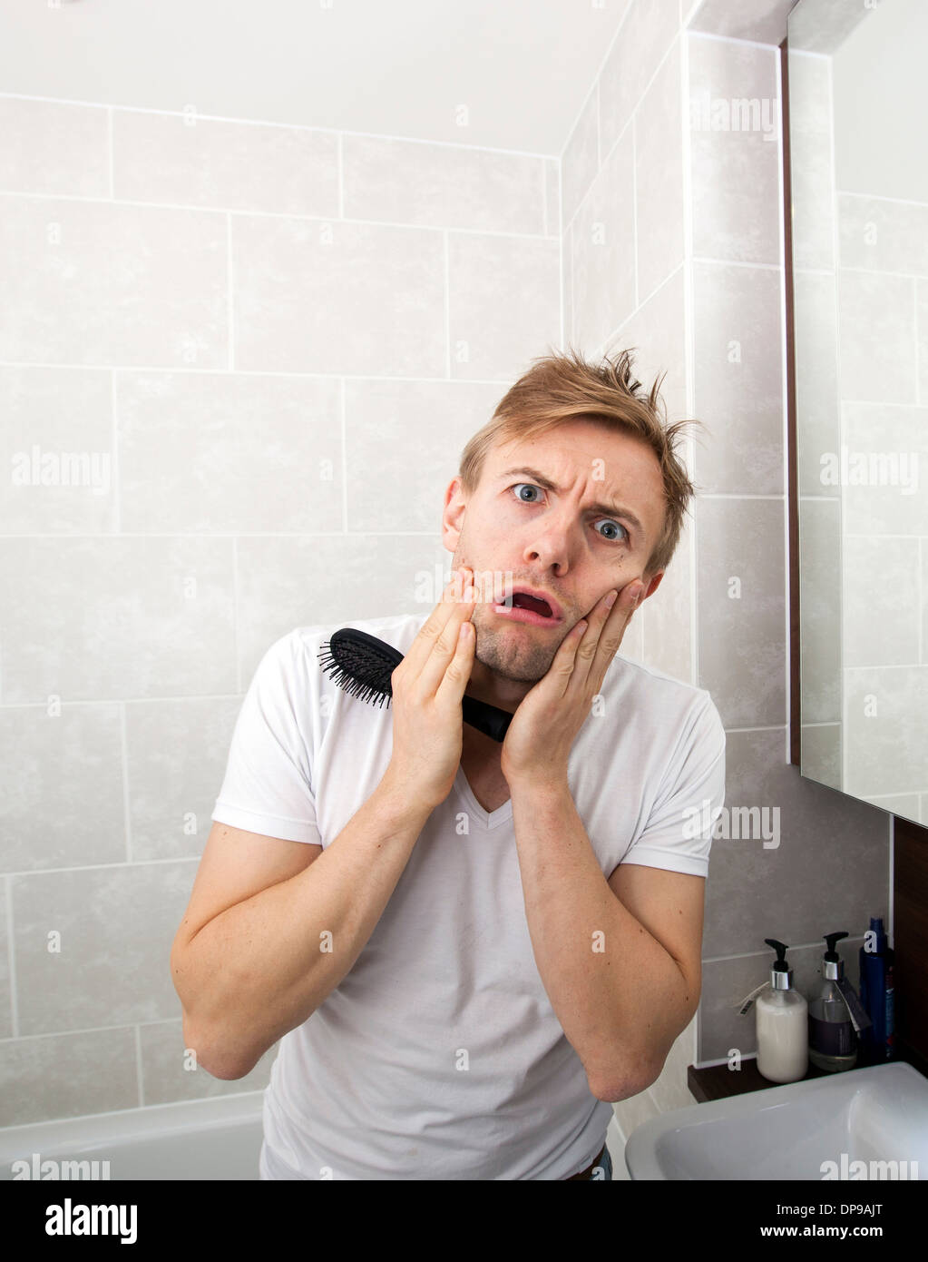 Portrait of man with hairbrush grimacing in bathroom Stock Photo