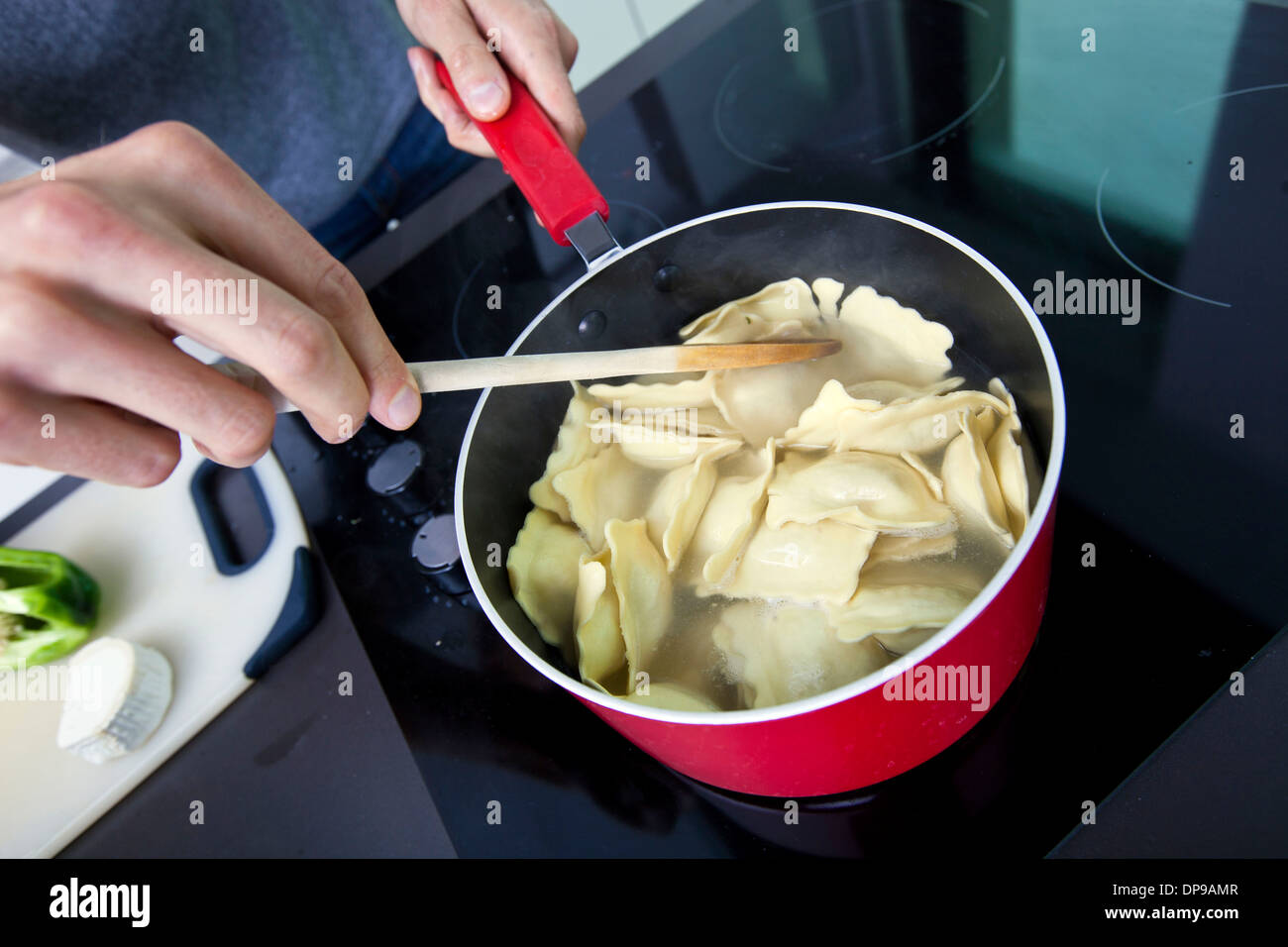 Midsection of man cooking pasta on stove in kitchen Stock Photo