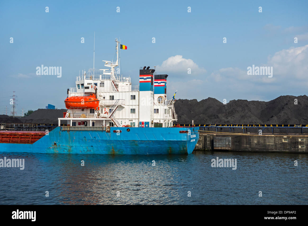 Bulk carrier docked in front of heaps of coal at SEA-invest / Ghent Coal Terminal / GCT, port of Ghent, East Flanders, Belgium Stock Photo