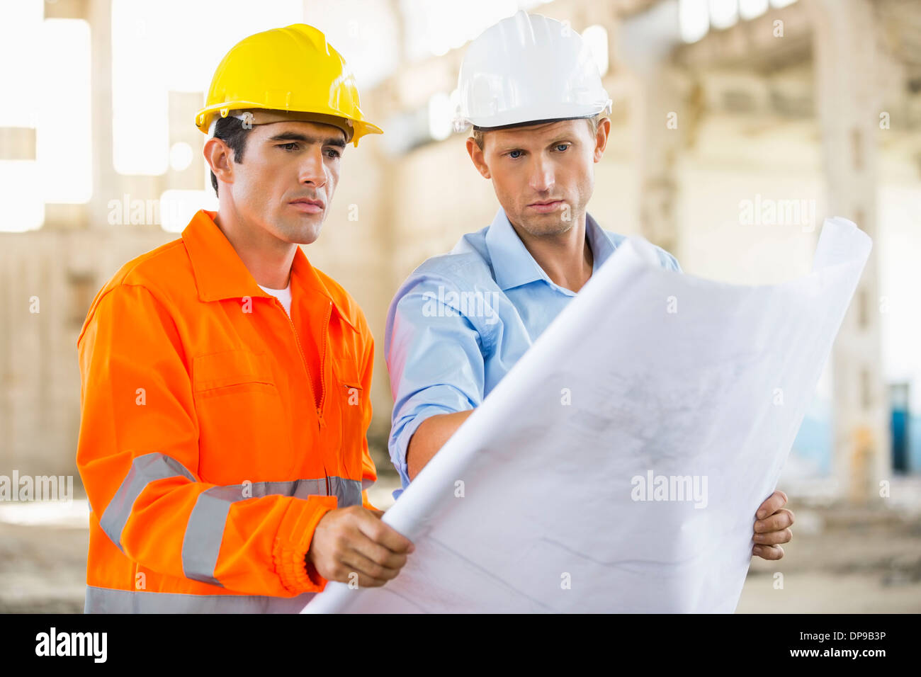 Male architects analyzing blueprint at construction site Stock Photo