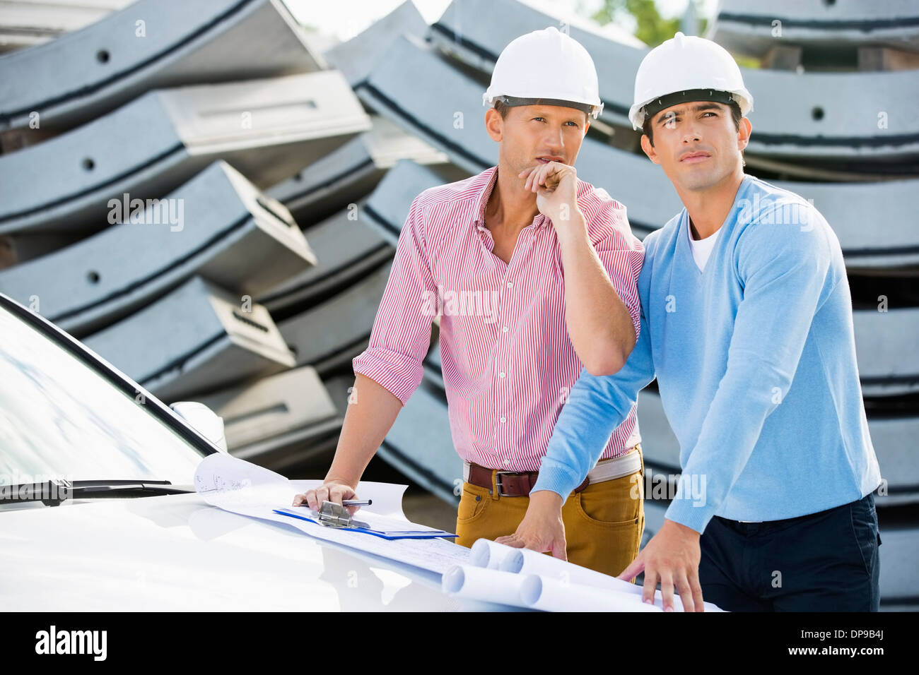 Architects with blueprints on car inspecting site Stock Photo