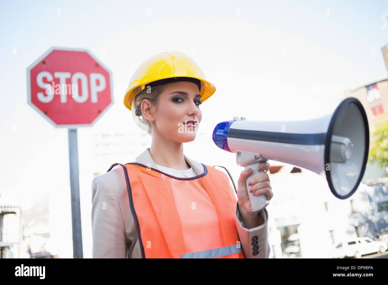 Serious businesswoman wearing builders clothes holding megaphone Stock Photo