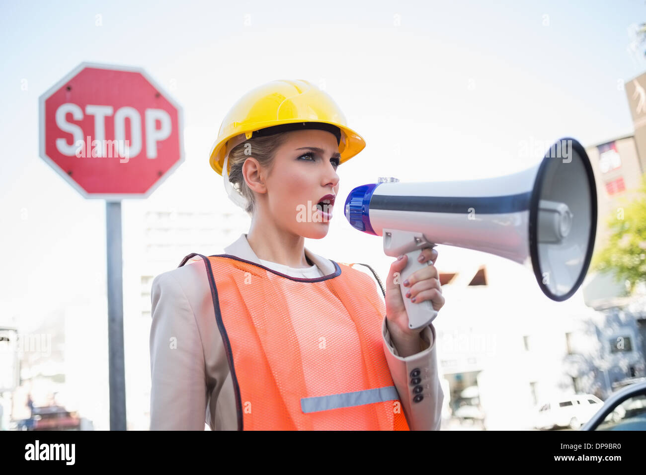 Businesswoman wearing builders clothes shouting in megaphone Stock Photo