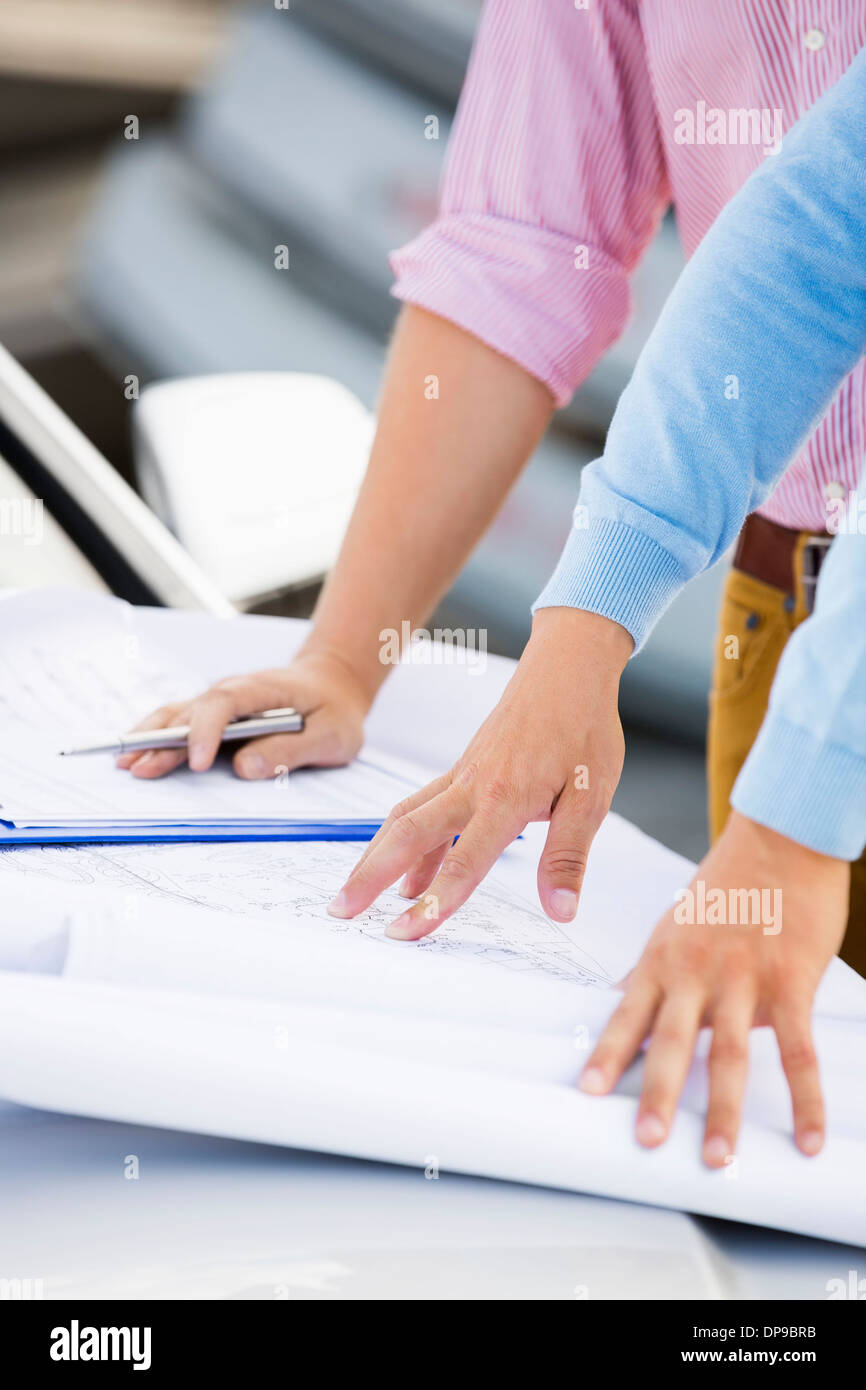 Cropped image of architects with blueprints on car at site Stock Photo