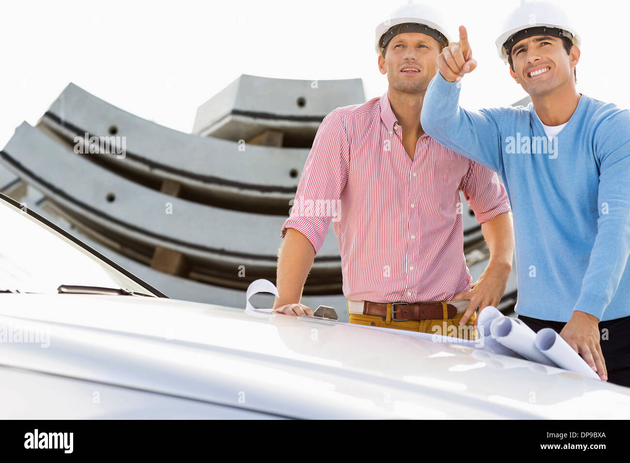 Architects with blueprints on car discussing at construction site Stock Photo