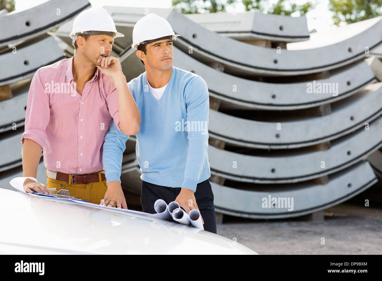 Architects with blueprints on car working at construction site Stock Photo