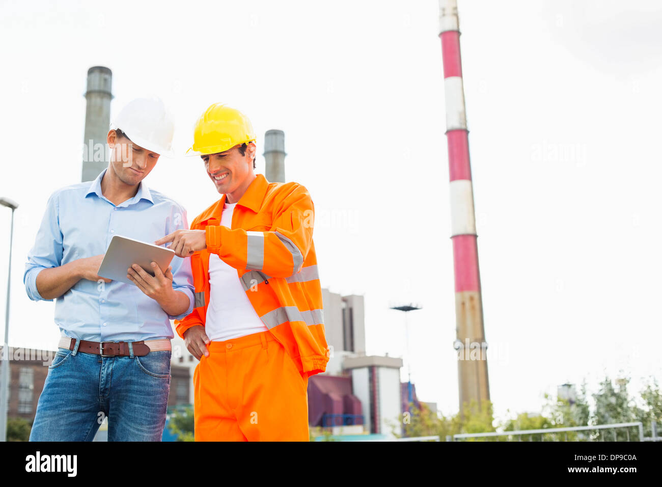 Two construction workers discussing over tablet PC at industry Stock Photo