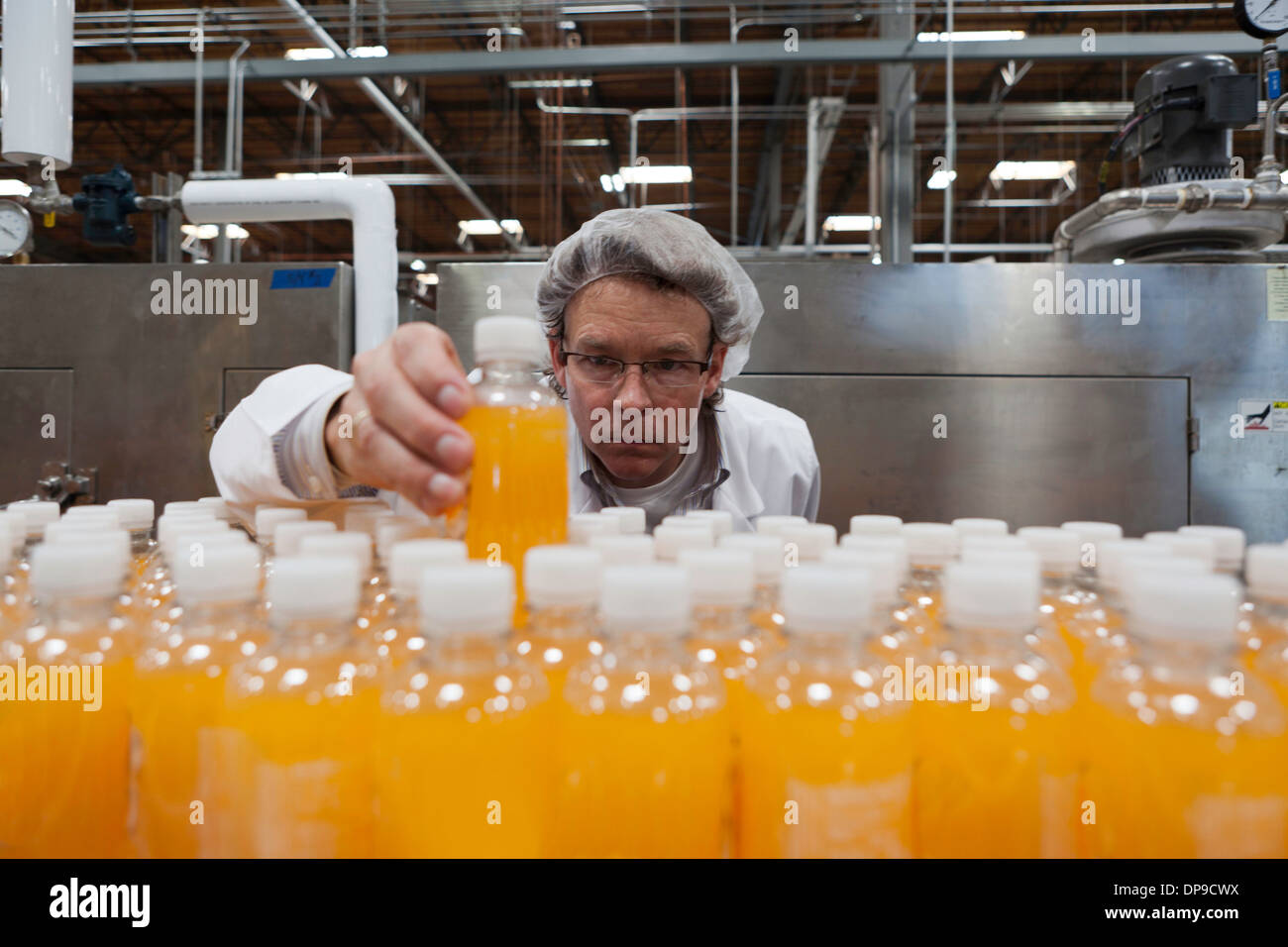 Industrial worker examining bottle in factory Stock Photo