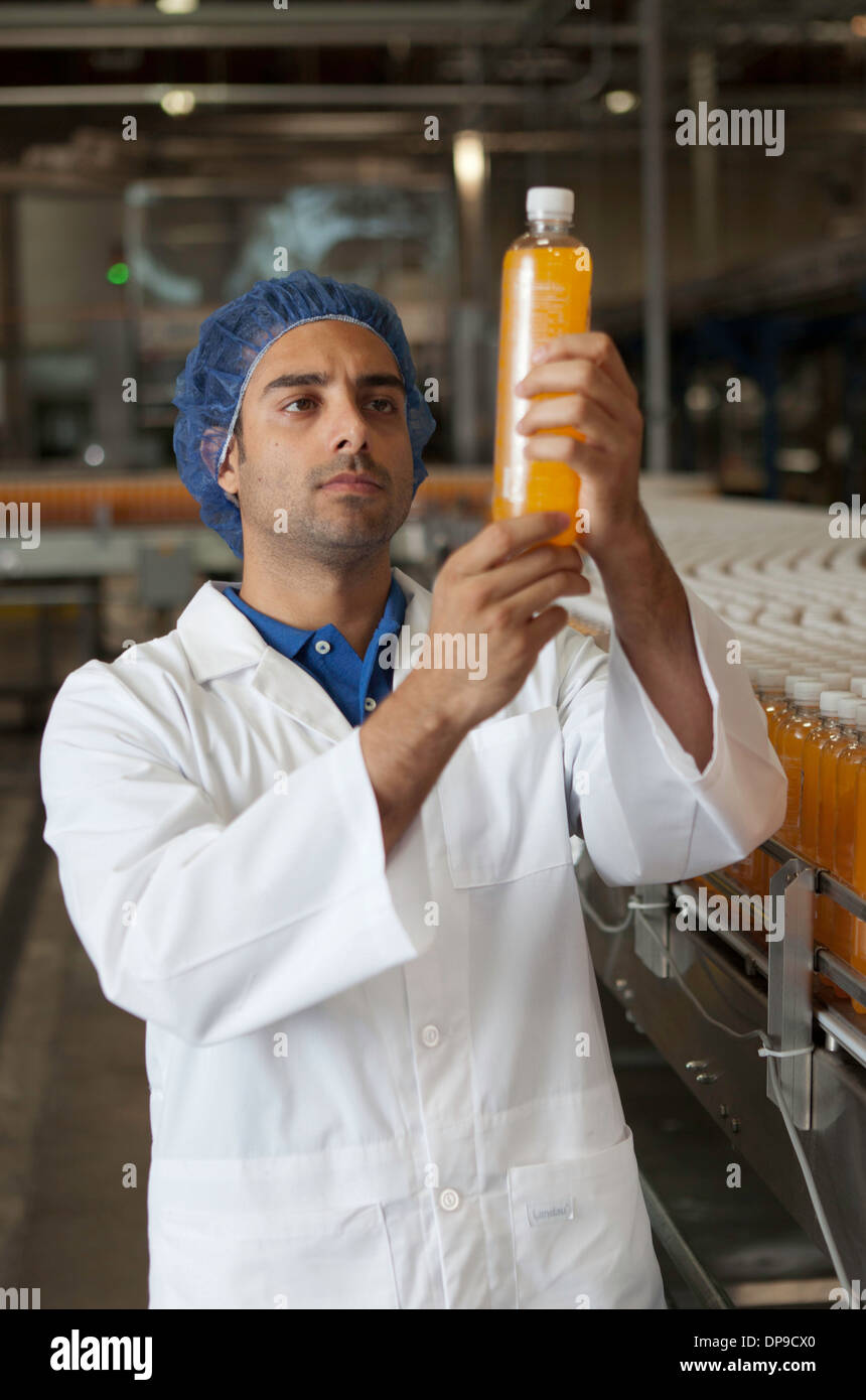 Mid adult industrial worker examining bottle in factory Stock Photo