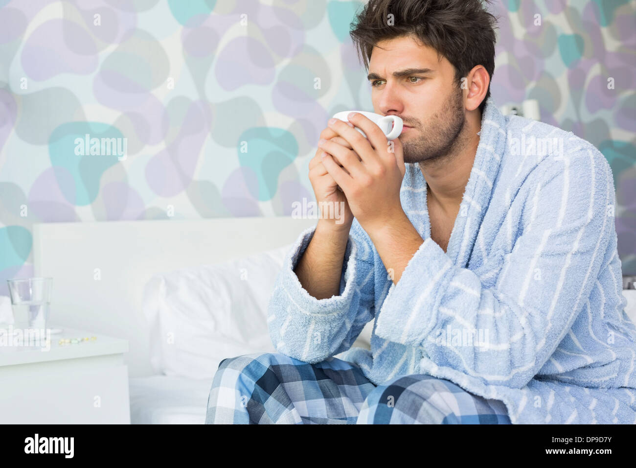 Sick man drinking coffee while sitting on bed at home Stock Photo Alamy