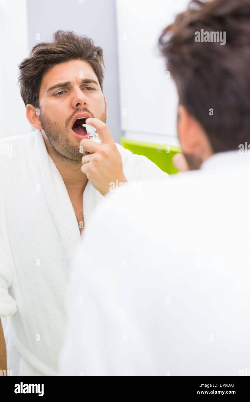 Reflection of man spraying medicine in mouth Stock Photo