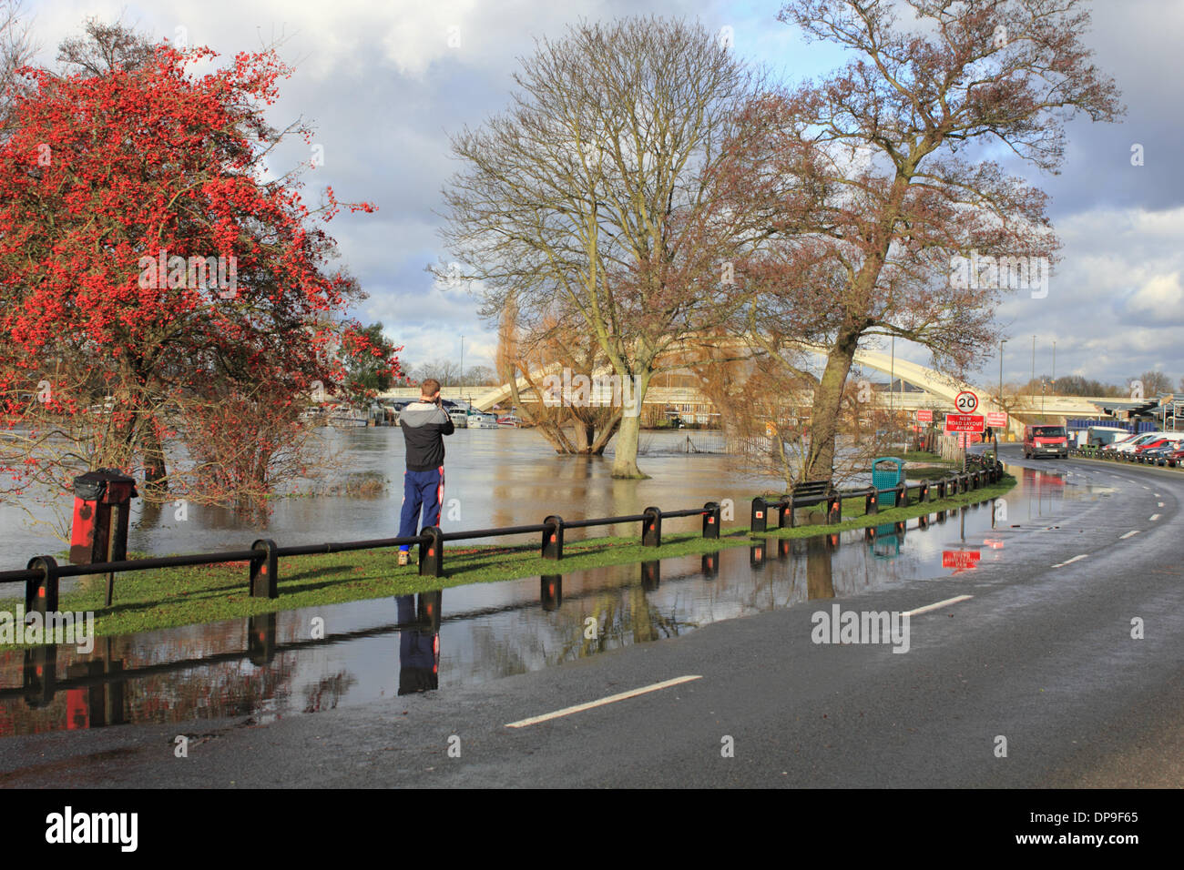 Walton-on-Thames, Surrey, England, UK. 9th January 2014. The River Thames has flooded at across Walton Lane and into the car park and picnic area next to Walton Bridge. A man takes a photograph of the floods. Credit:  Julia Gavin/Alamy Live News Stock Photo