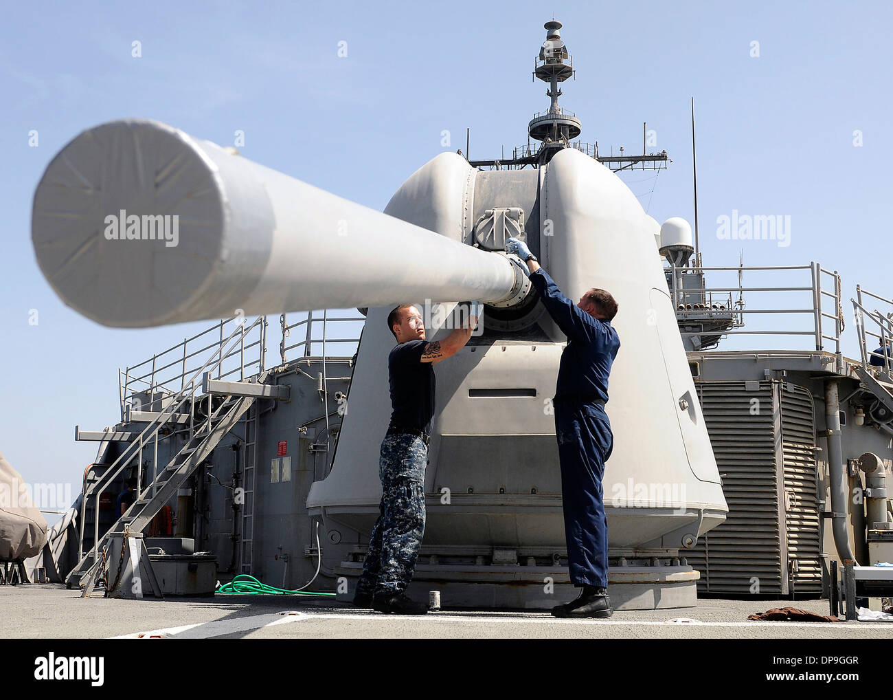 U.S. Sailors perform maintenance on a Mk 45 5-inch lightweight gun on the USS Bunker Hill Stock Photo