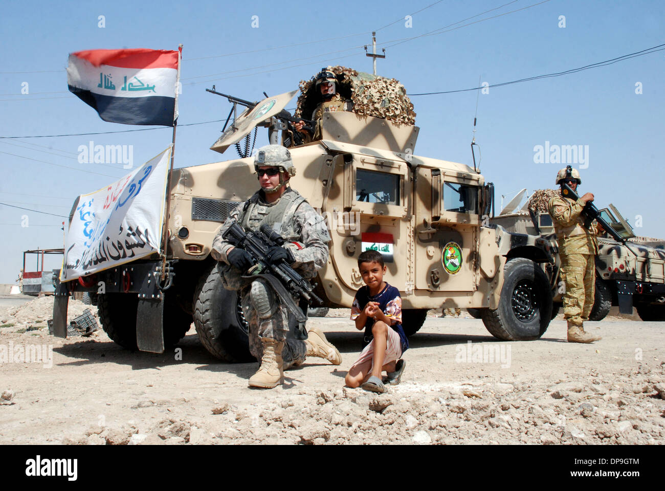 U.S. soldier provides security, along with a local child, in Basra Province, Iraq Stock Photo