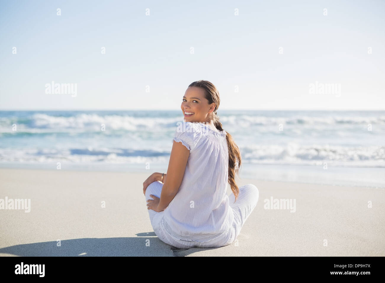 Rear view of smiling woman looking over shoulder at camera Stock Photo