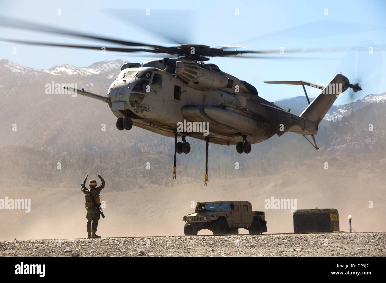 U.S. Marine directs the pilots of a CH-53E Super Stallion helicopter after releasing a Humvee Stock Photo