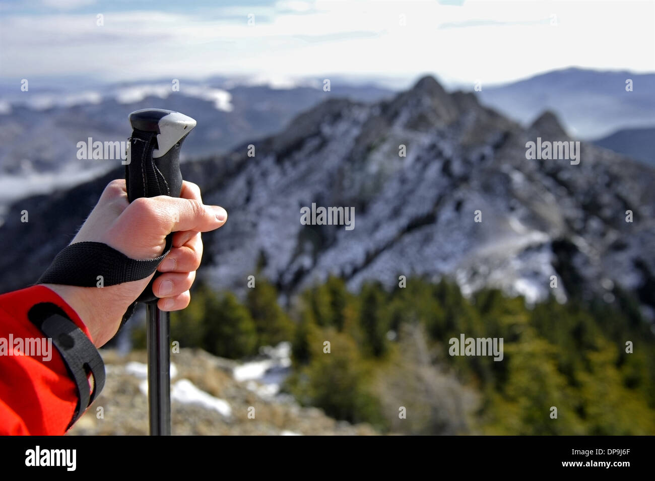 Hand of a man holding a hiking pole on top of a mountain Stock Photo