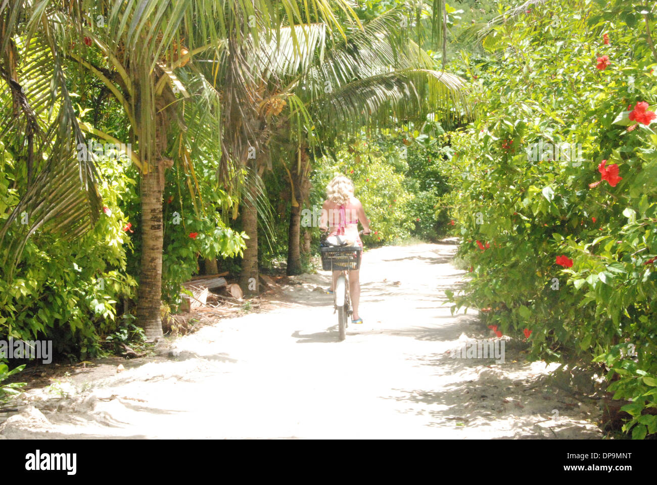 Girl riding a bike through through a tropical forest Stock Photo