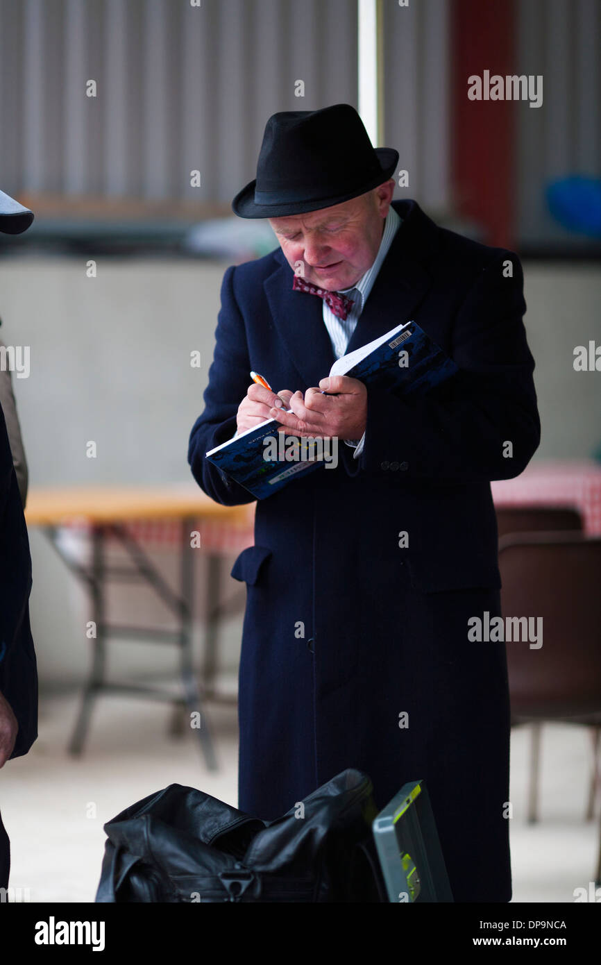 A man makes and entry into his ledger at a rural community farm festival in Ireland Stock Photo