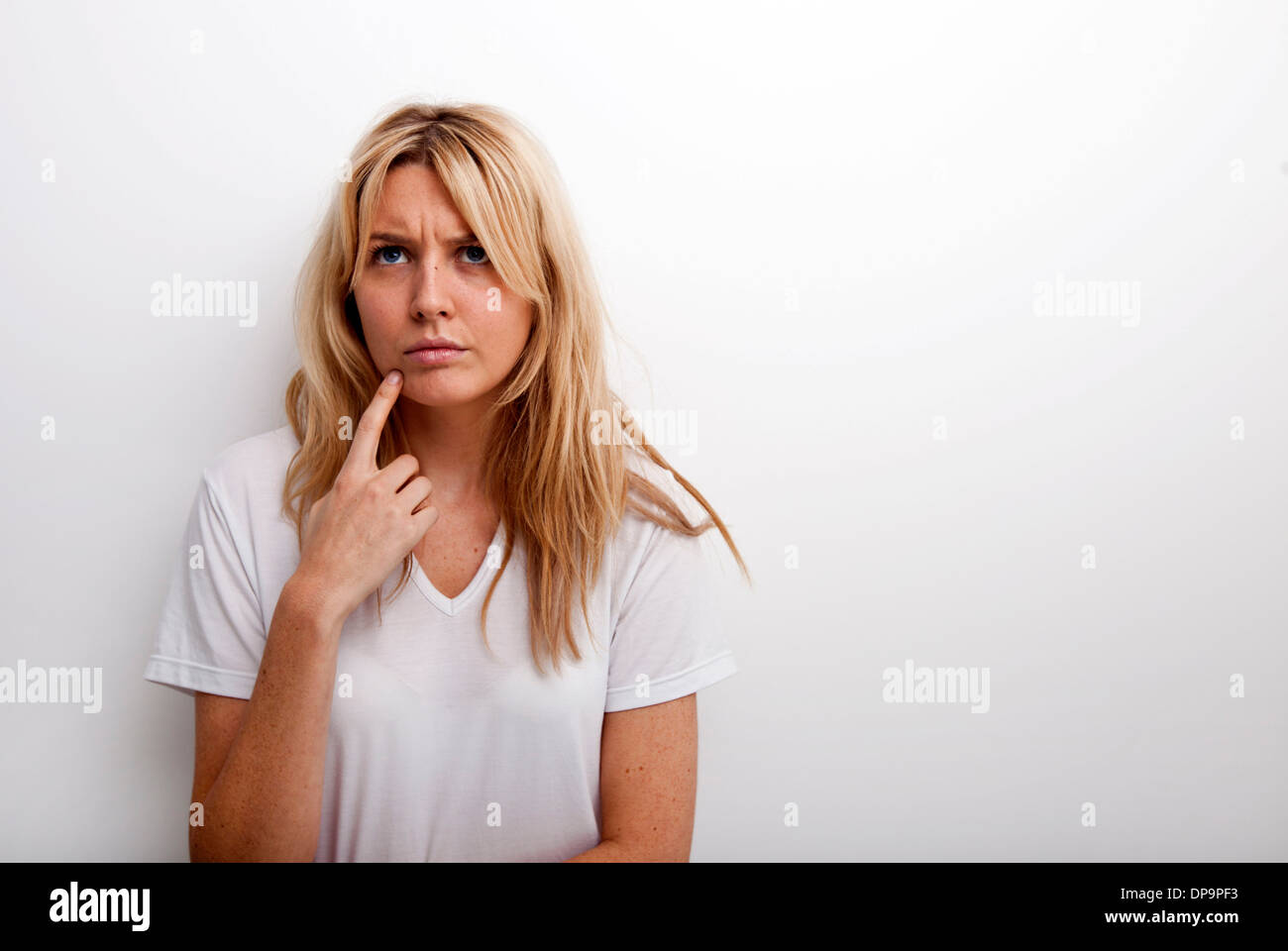 Thoughtful woman standing against white background Stock Photo