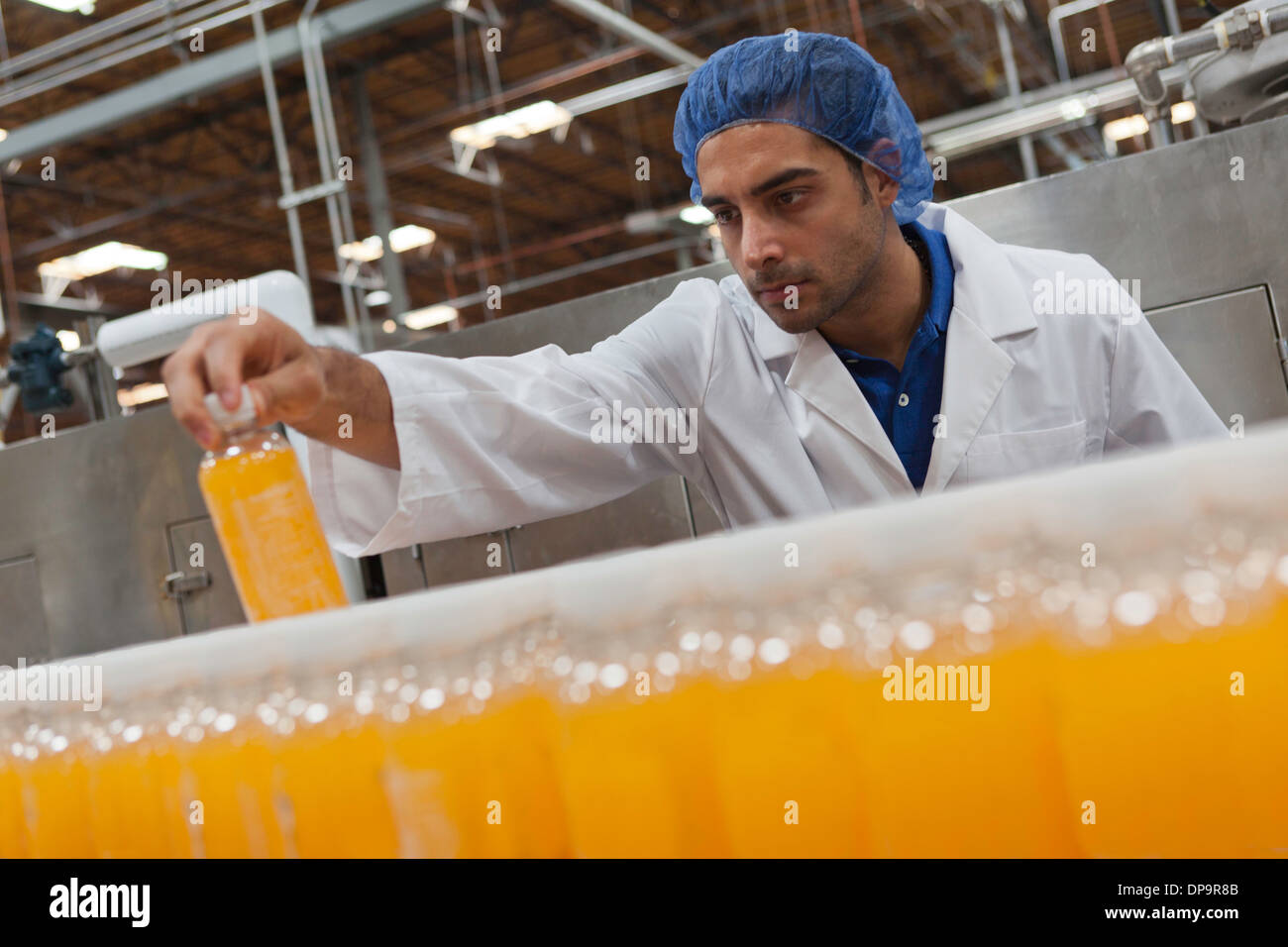 Mid adult industrial worker looking at bottle in factory Stock Photo