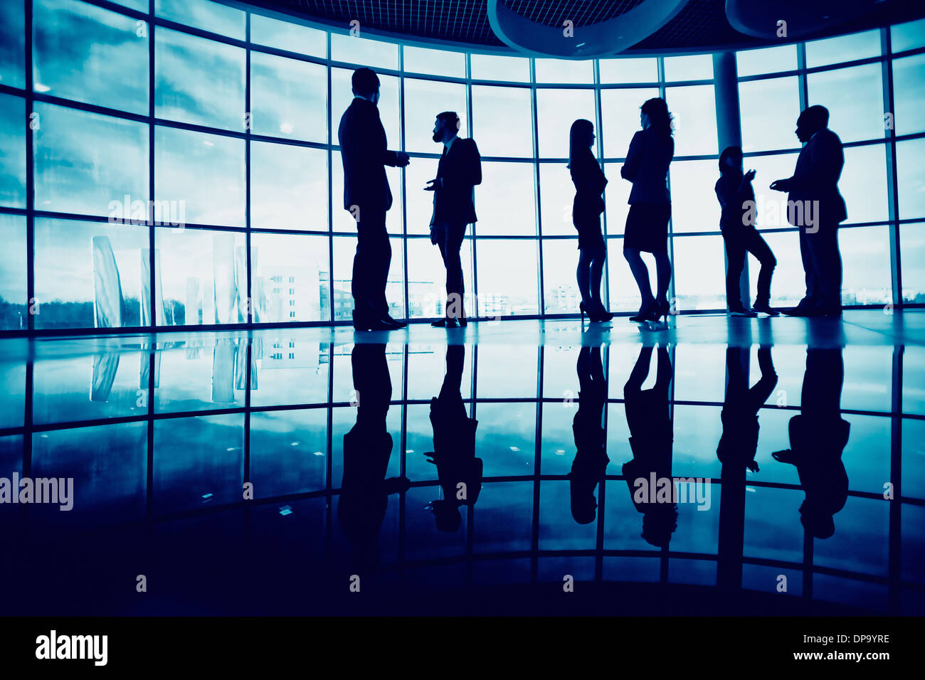 Several white collar workers communicating in office against window Stock Photo