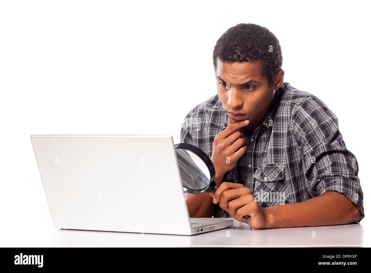 african man looking through a magnifying glass on his laptop Stock Photo