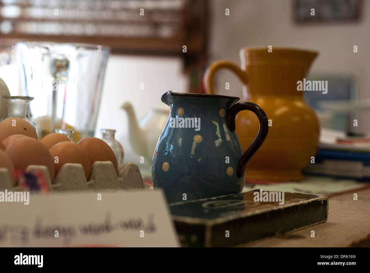 A table top of colourful clutter of jugs, teapots, eggs bit and bobs Stock Photo