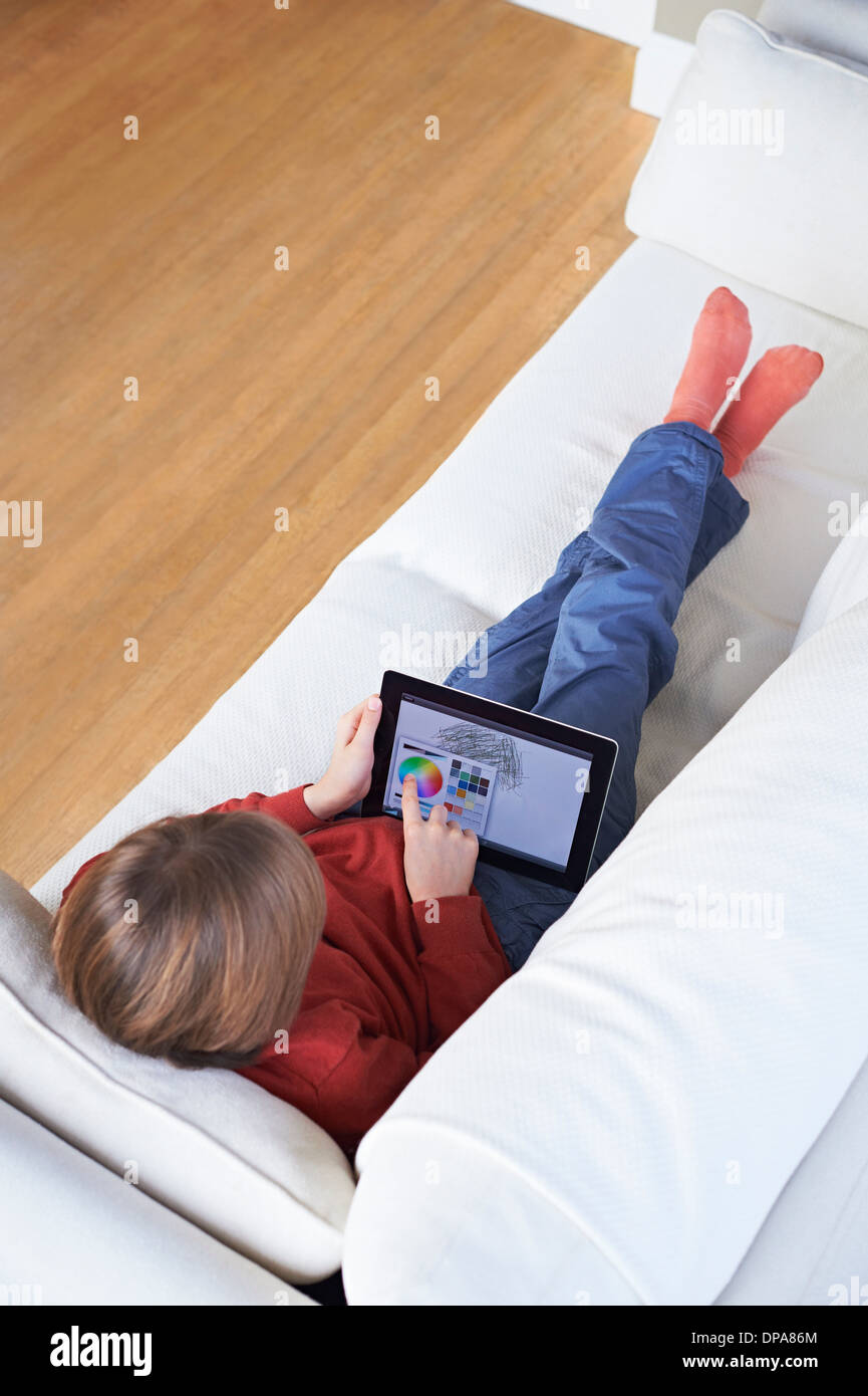 Boy on sofa using digital tablet Stock Photo