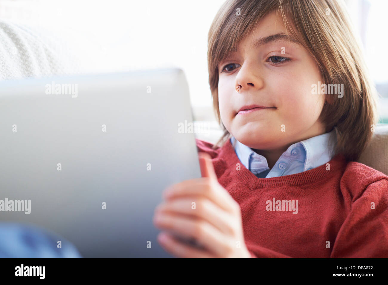 Boy on sofa using digital tablet Stock Photo