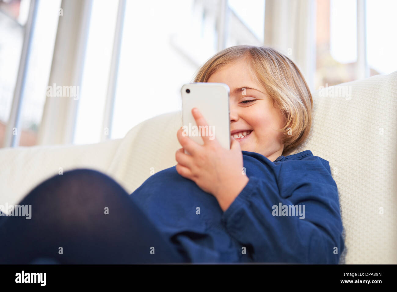 Girl on sofa using smartphone Stock Photo