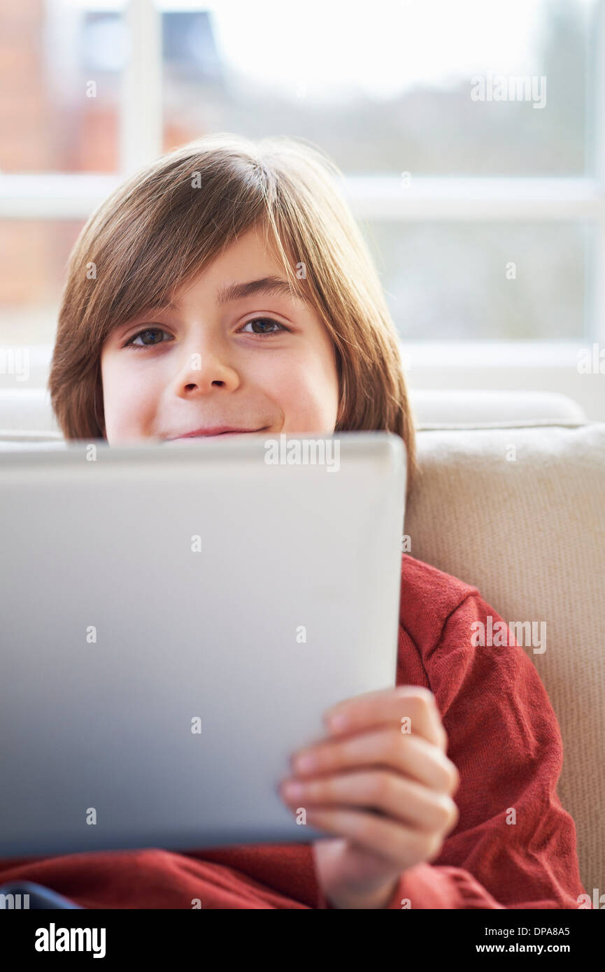 Boy on sofa using digital tablet Stock Photo