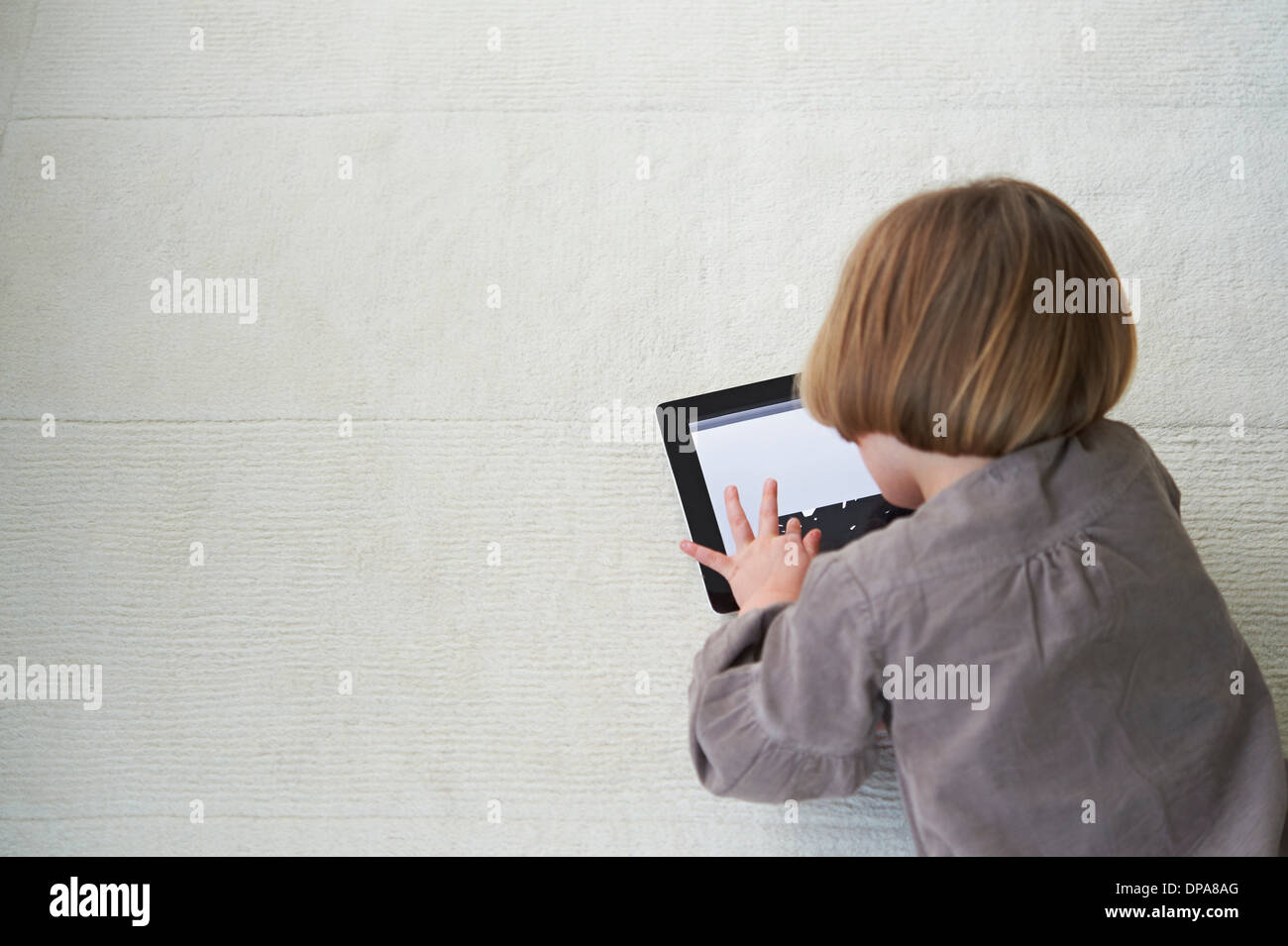 Girl lying on floor using digital tablet Stock Photo