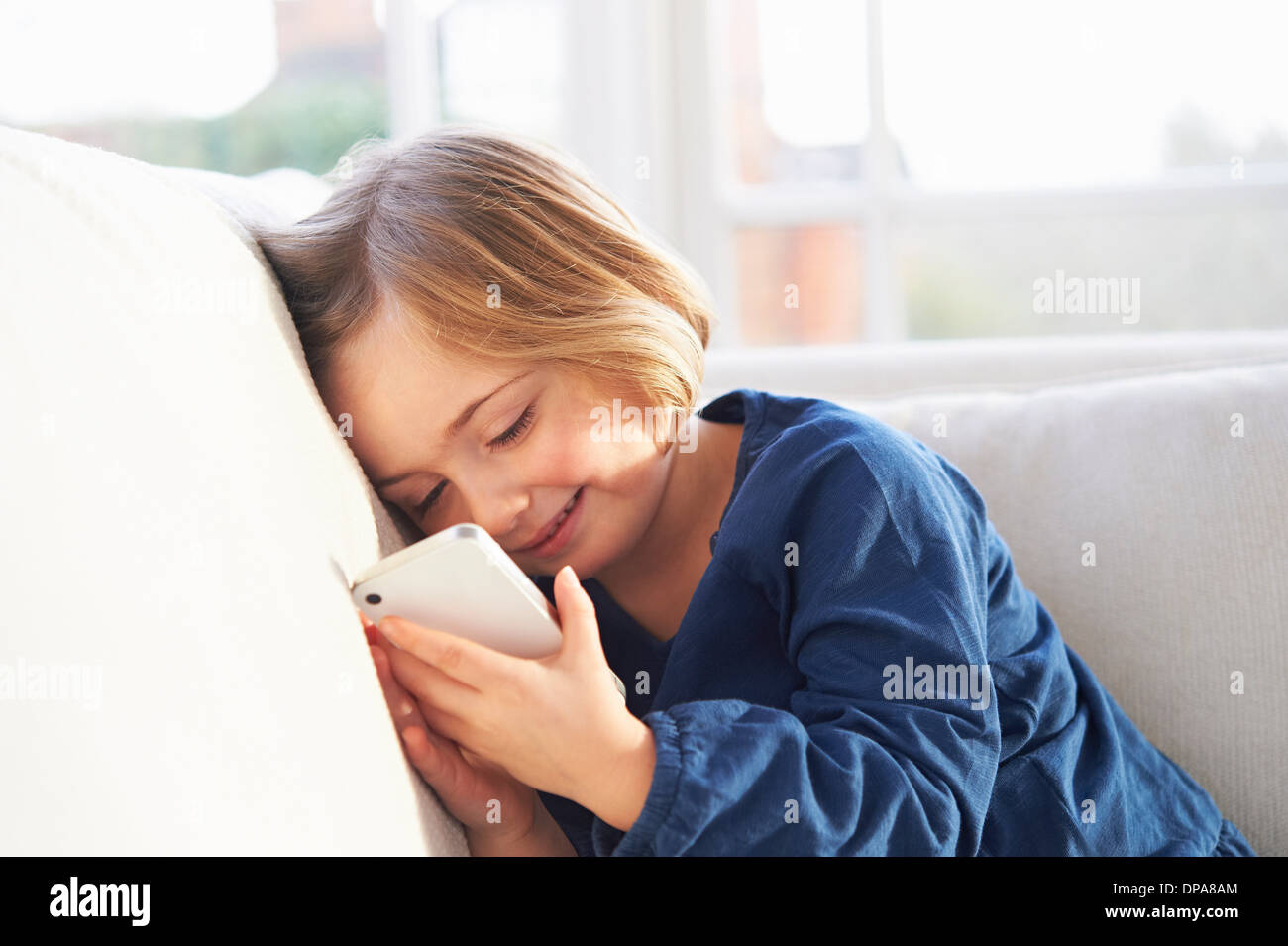Girl on sofa using smartphone Stock Photo