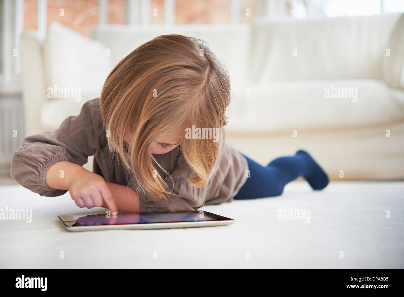 Girl lying on floor using digital tablet Stock Photo